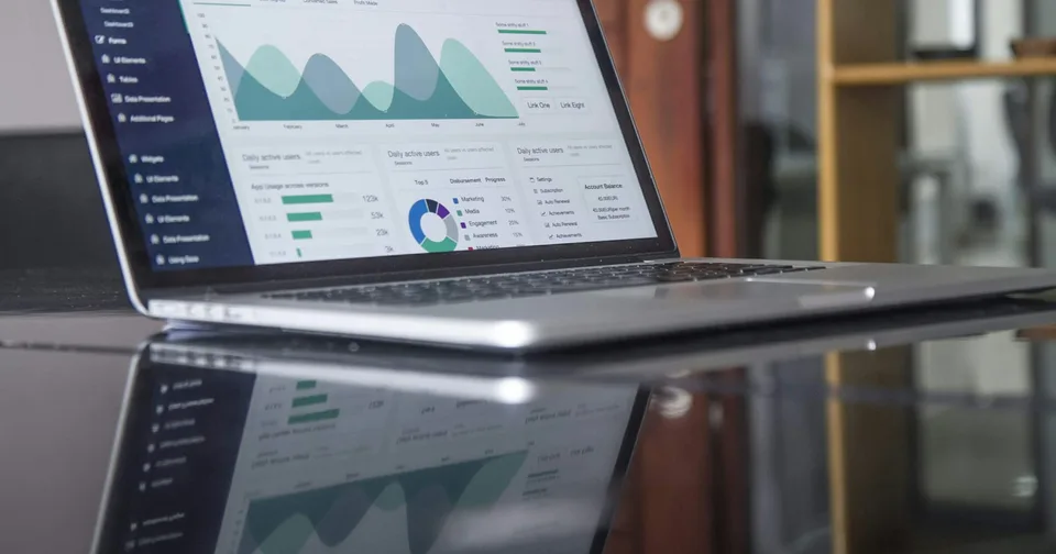 Website traffic reports open on a laptop beside a notebook